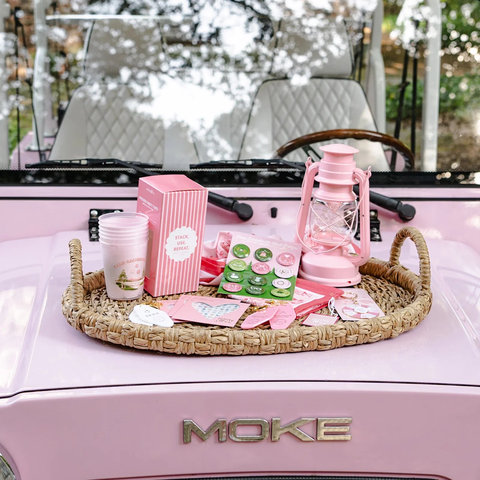 Rattan tray on pink vehicle hood filled with Camp Bachelorette flex cups and lantern décor