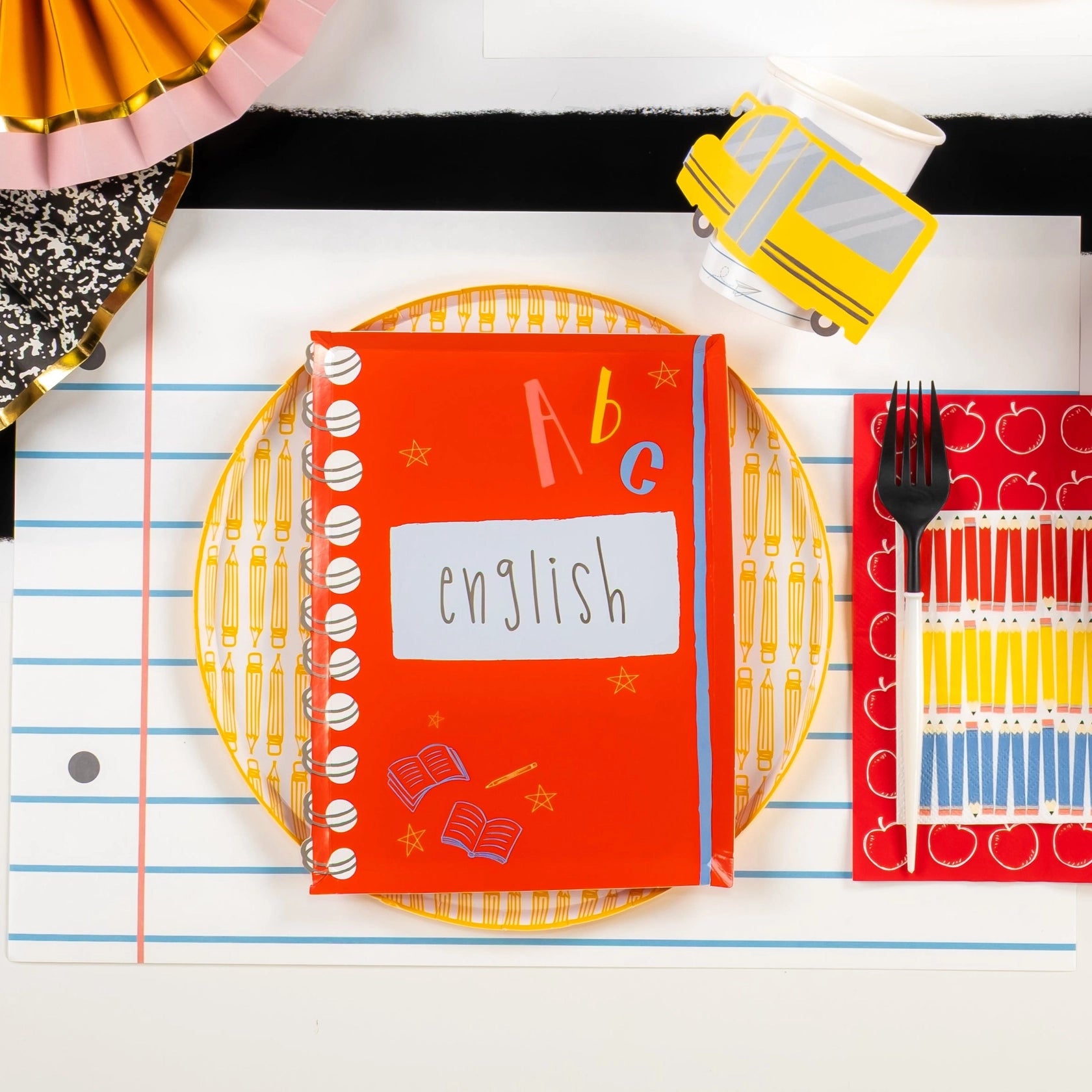 Red ‘English’ notebook plate setting on lined-paper placemat with apple towel.