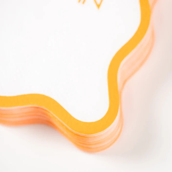 Stack detail of white cocktail napkins with orange scalloped border.