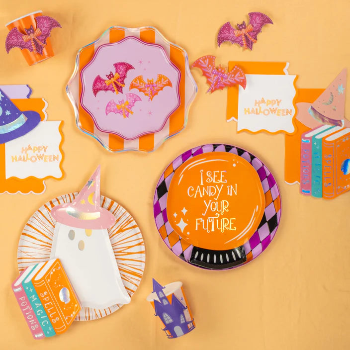 Party flat lay showing harlequin diamond dinner plate beside pink bats plate, bat stickers, and Halloween cards.