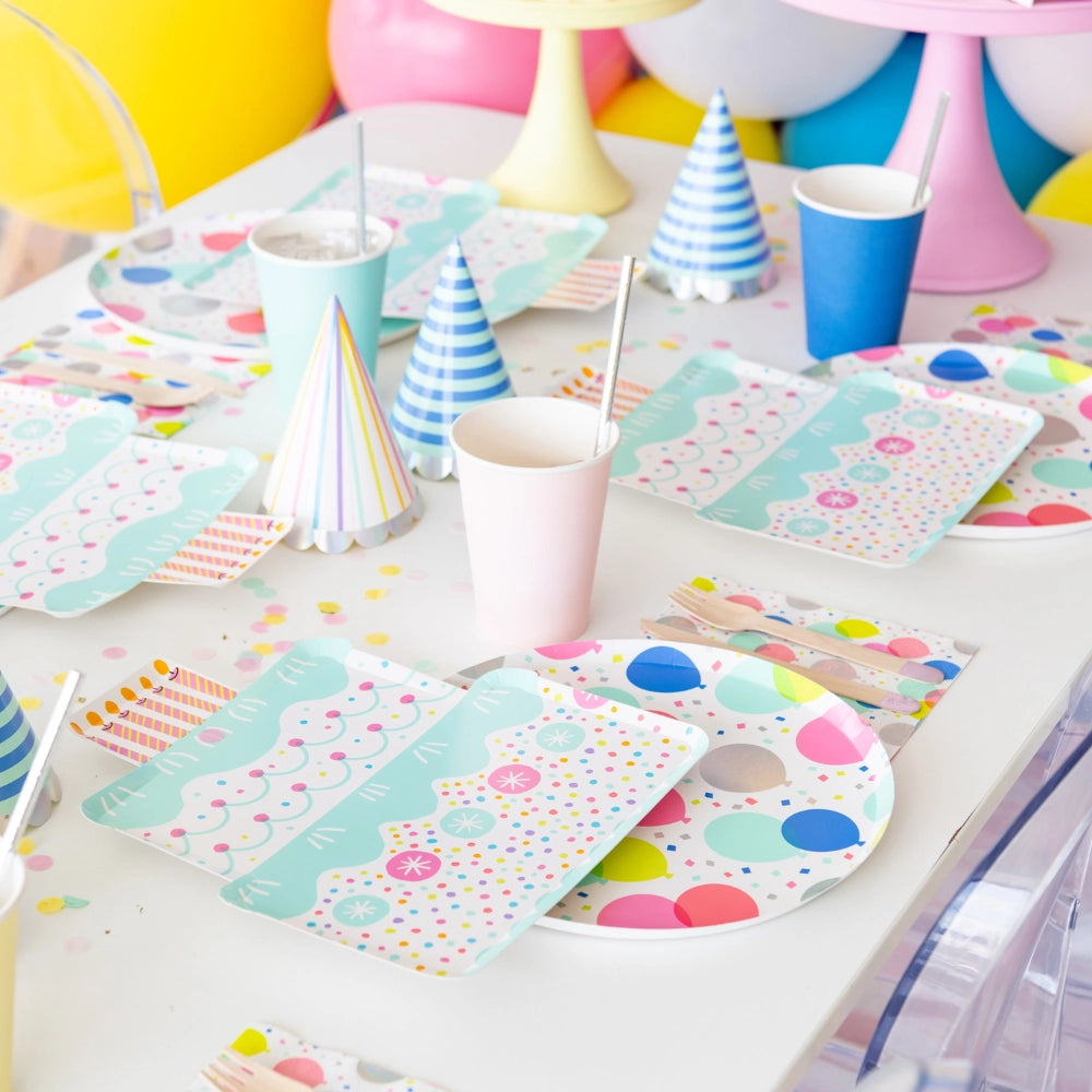 Side view of balloon plate and coordinating napkin on white table with party hats and pastel cups—ideal for adult or kids’ birthdays	
