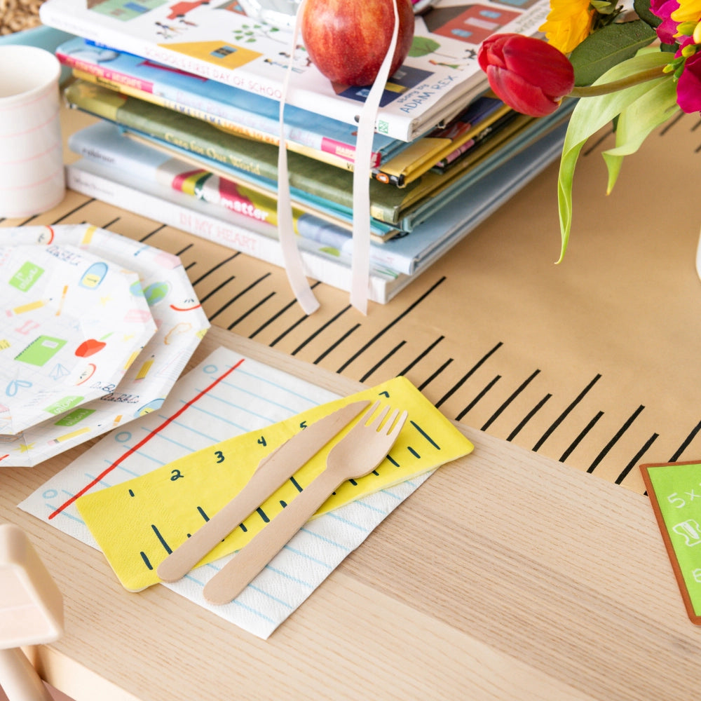 Lifestyle table scene showing notebook napkin under yellow ruler napkin and wood utensils