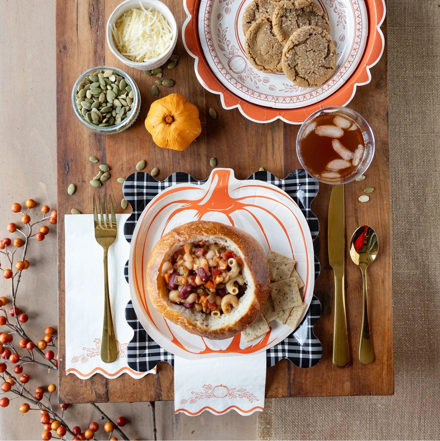 Tablescape with pumpkin plate, bread bowl chili, gold flatware, and napkin