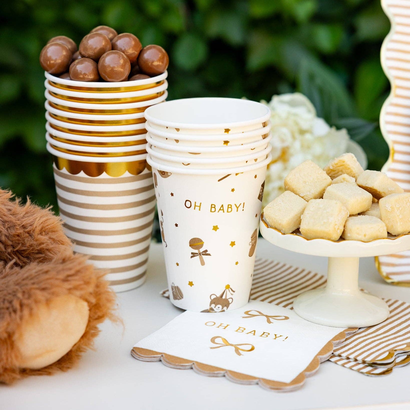 Neutral baby shower table setup with tan striped cups and dessert display
