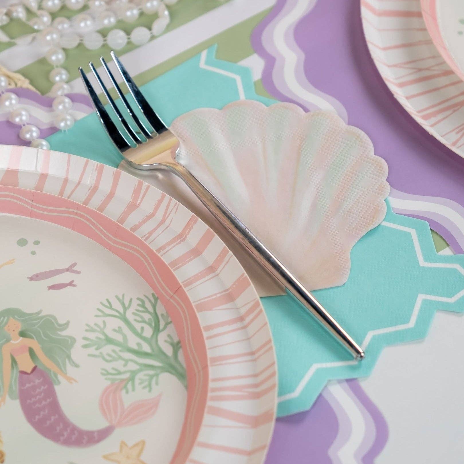 ocean cocktail napkins placed under plate with pastel tableware.