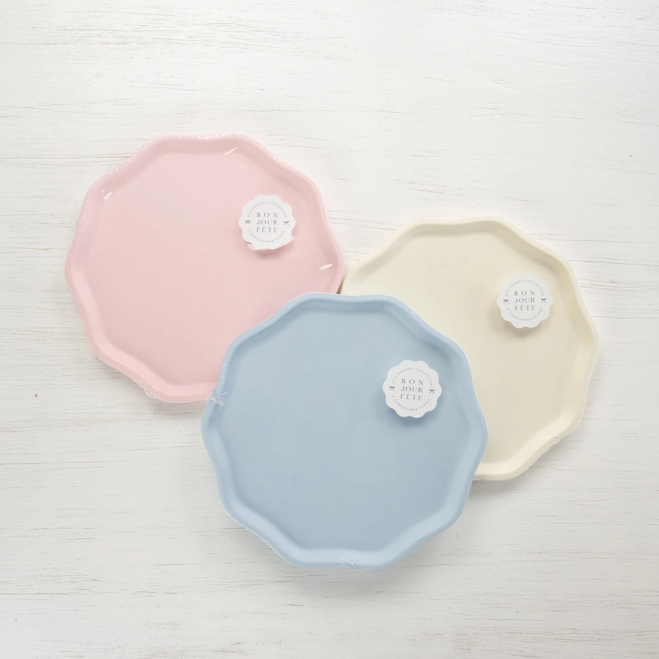 Packaged compostable plates in petal pink, sky blue, and cream—Bonjour Fête Signature Line.