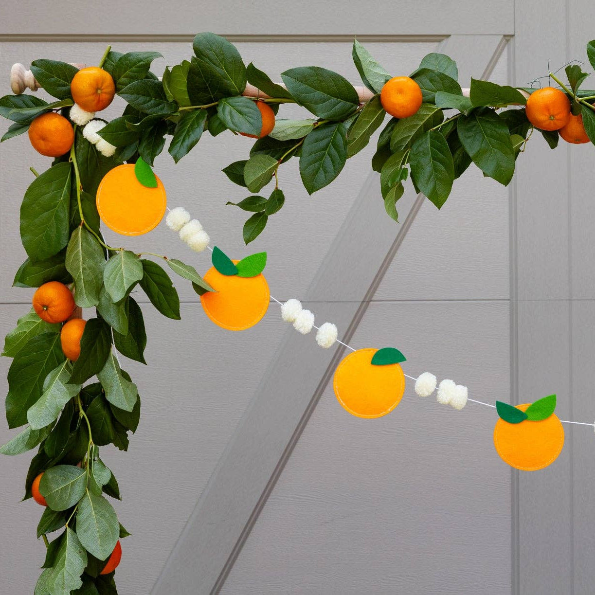 Orange felt banner draped across greenery for a summer party setup.