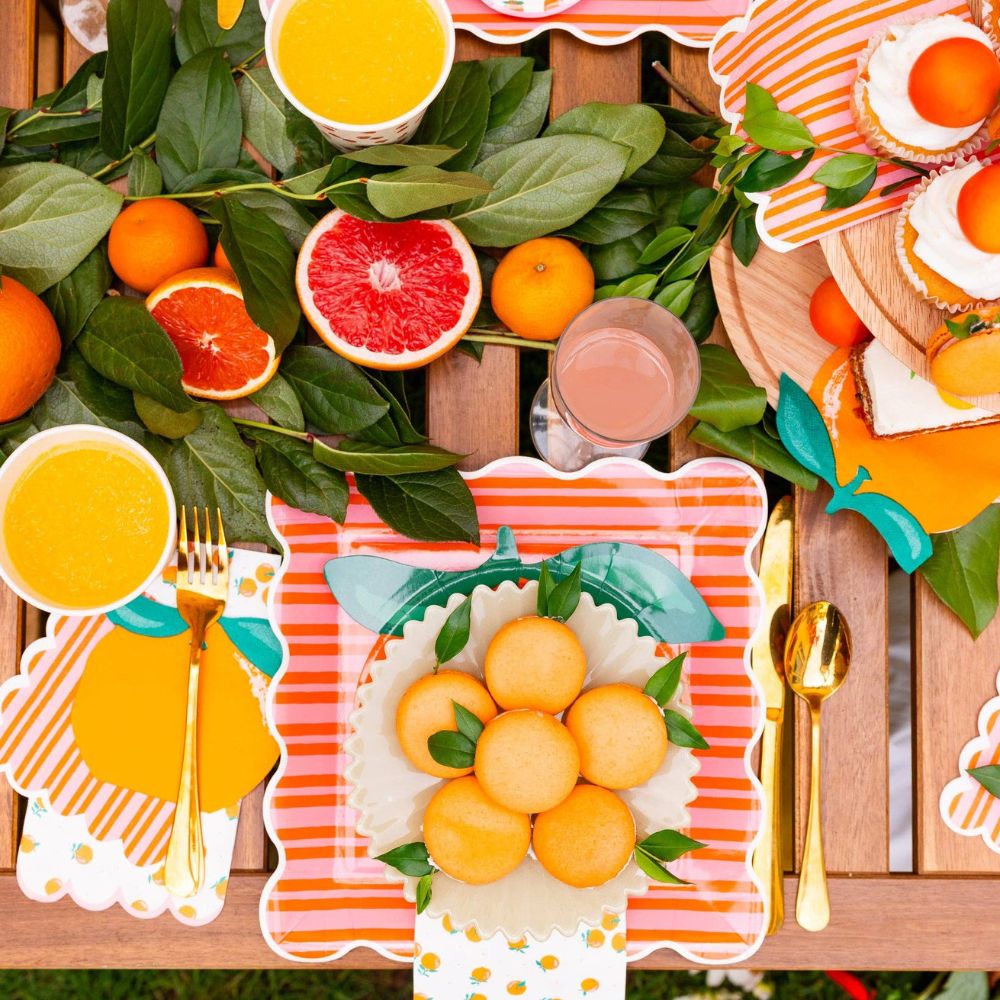 Orange dinner napkins on a citrus-themed summer party table.
