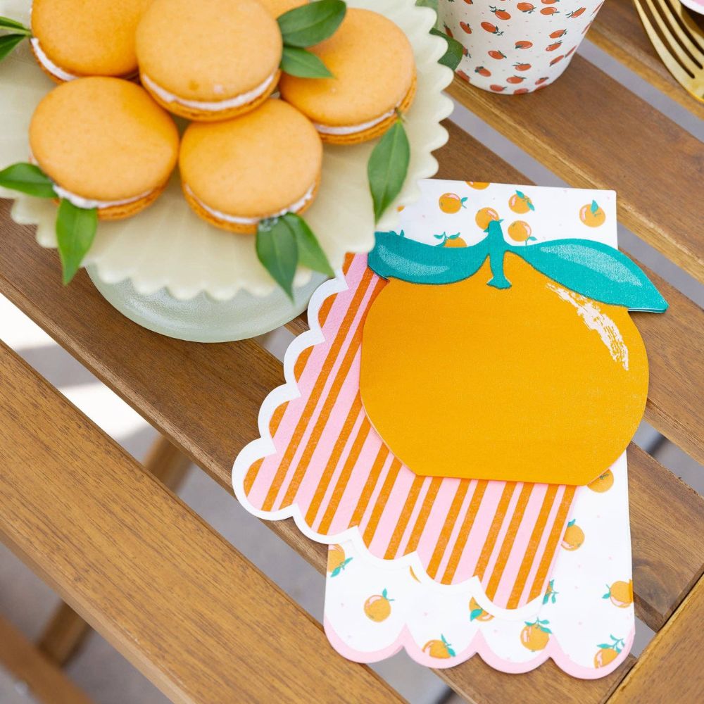 Orange dinner napkins styled with citrus party plates and macarons.
