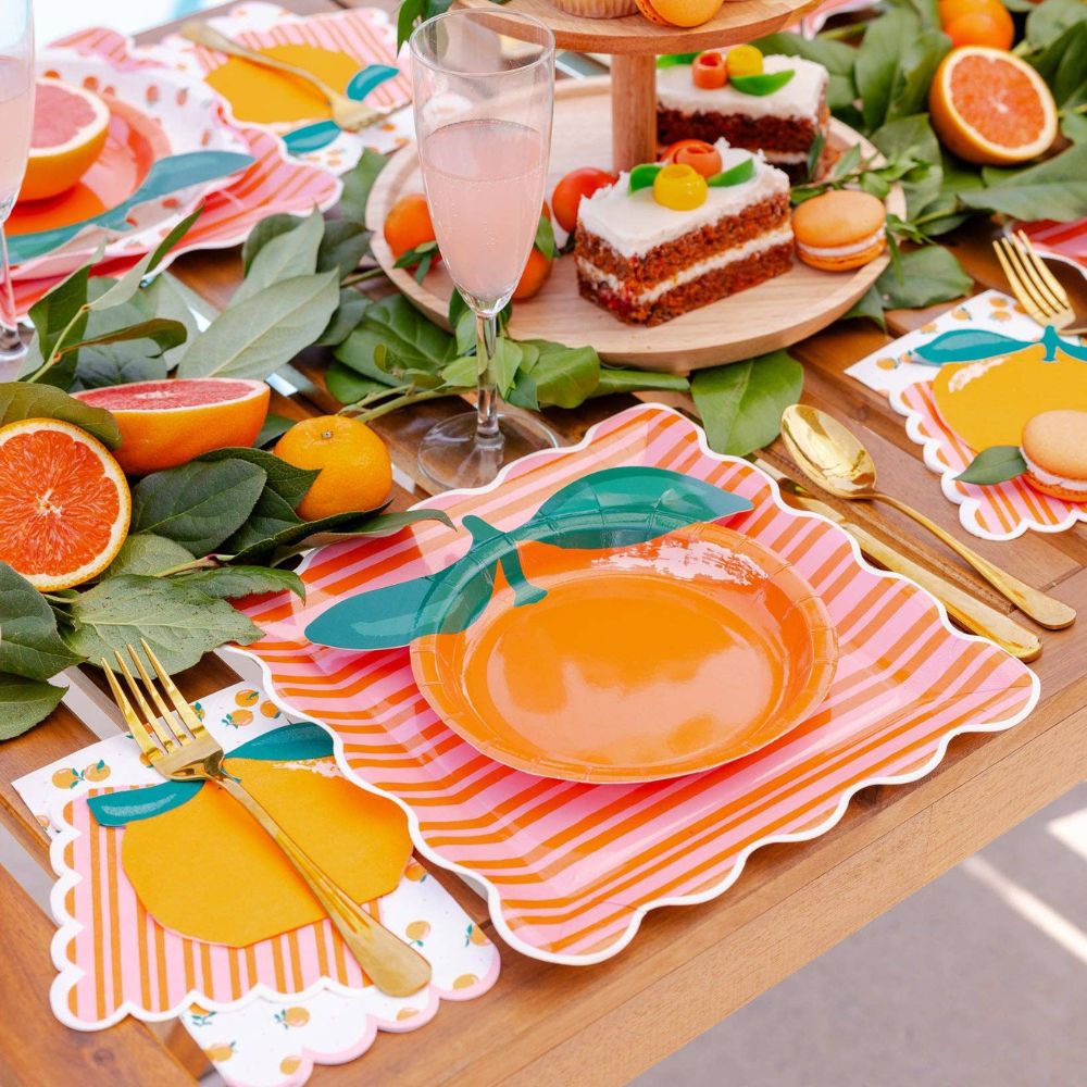Orange dinner napkin paired with orange plates and gold party flatware.
