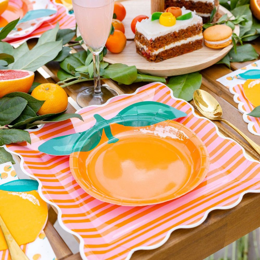 Orange shaped plate styled on a citrus-themed party table.
