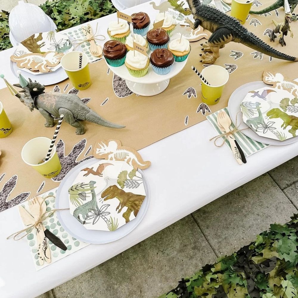 outdoor dinosaur birthday table with plates and cupcake display
