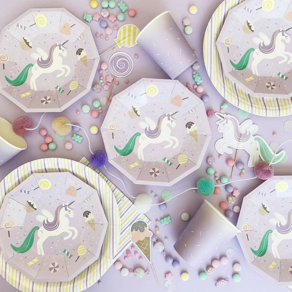 Overhead flat lay of unicorn plates, cups, and assorted magical party favors