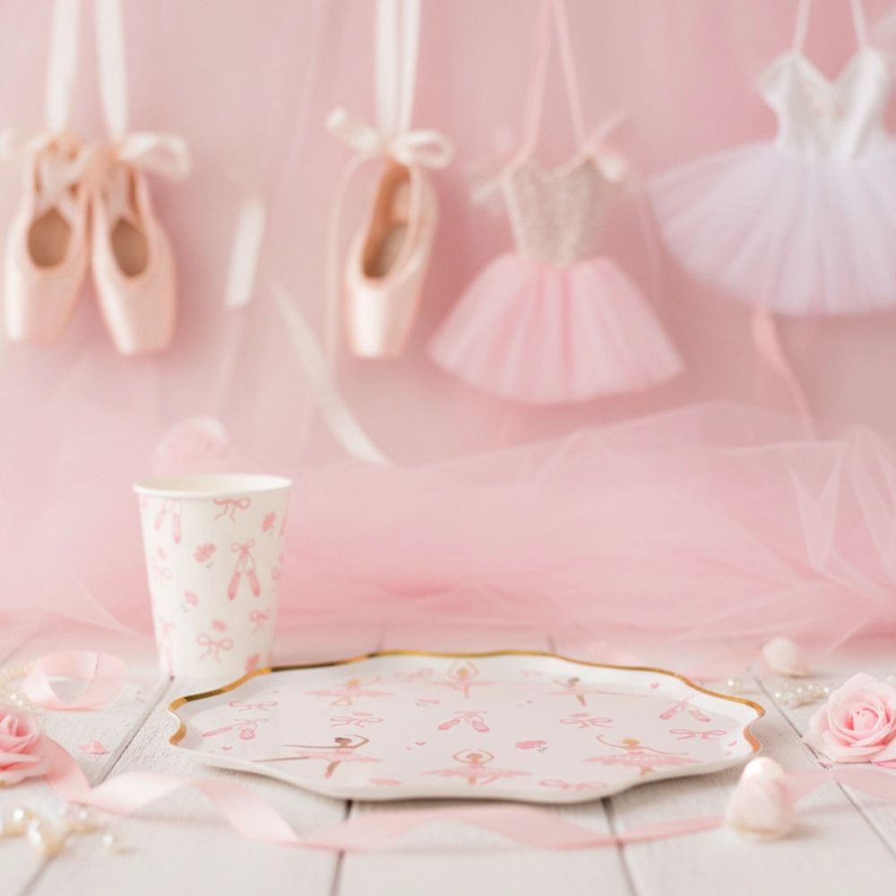 Ballerina cup on a wooden surface with pink tulle and ballet slippers