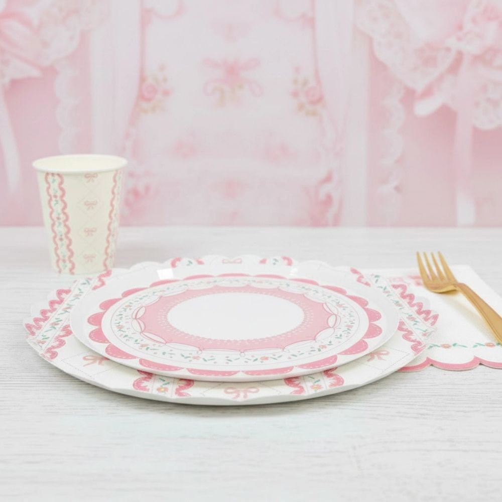 Place setting with stacked pink plates and a gold fork on white wood
