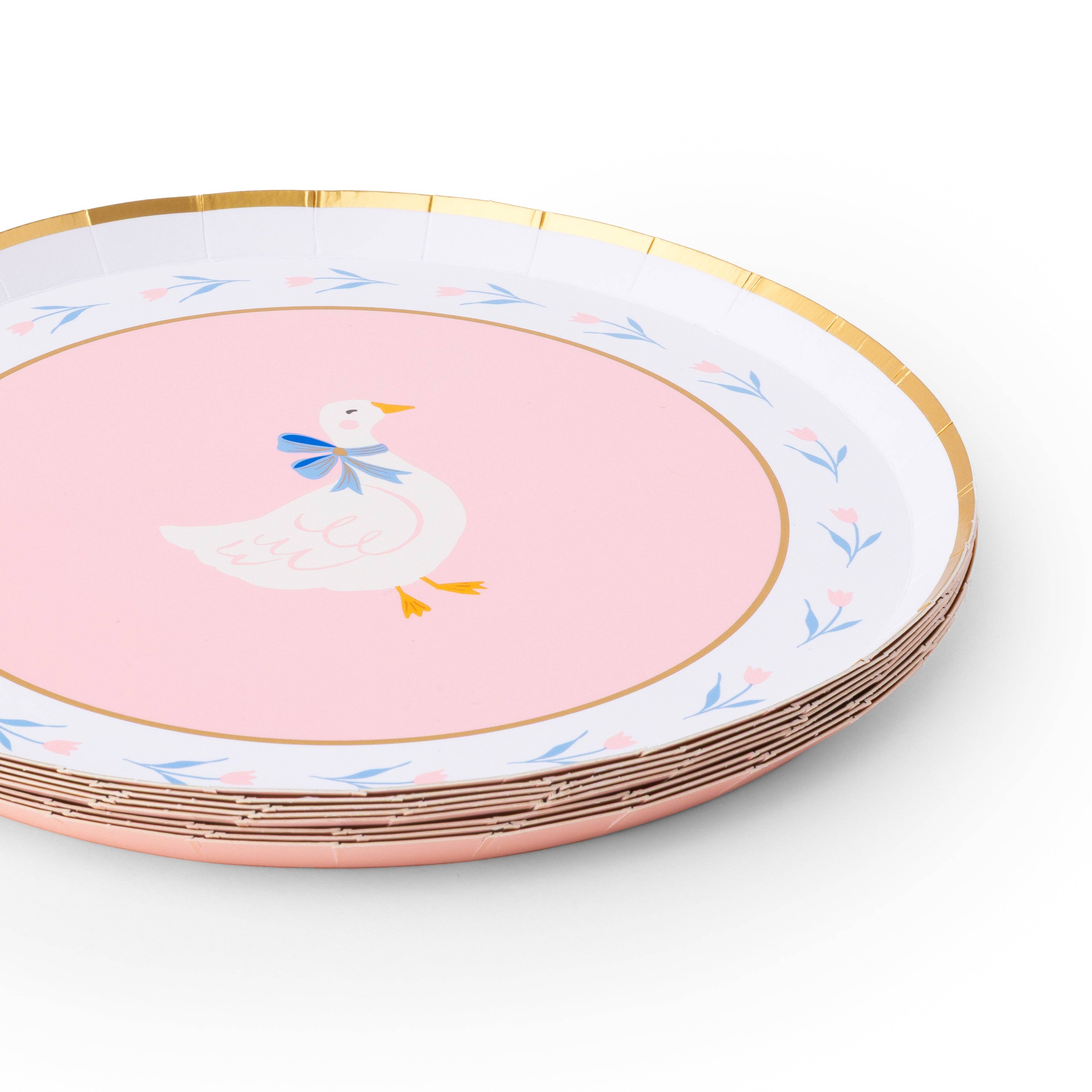Stack of pink goose dessert plates with gold rim detail.