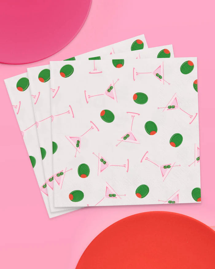 Fanned stack of pink and green martini print cocktail napkins with colorful plates on a pink background
