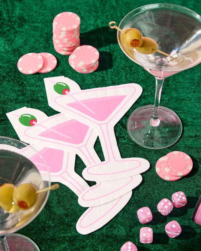 Stack of pink martini napkins styled on green velvet with real martini glasses, pink poker chips, and dice for casino night