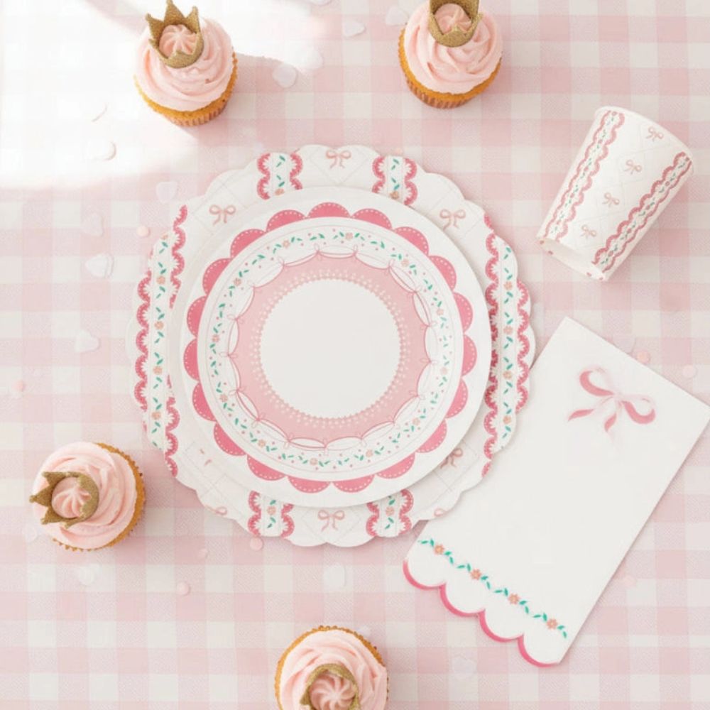 Overhead view of a coquette plate surrounded by crown cupcakes and ribbon napkins
