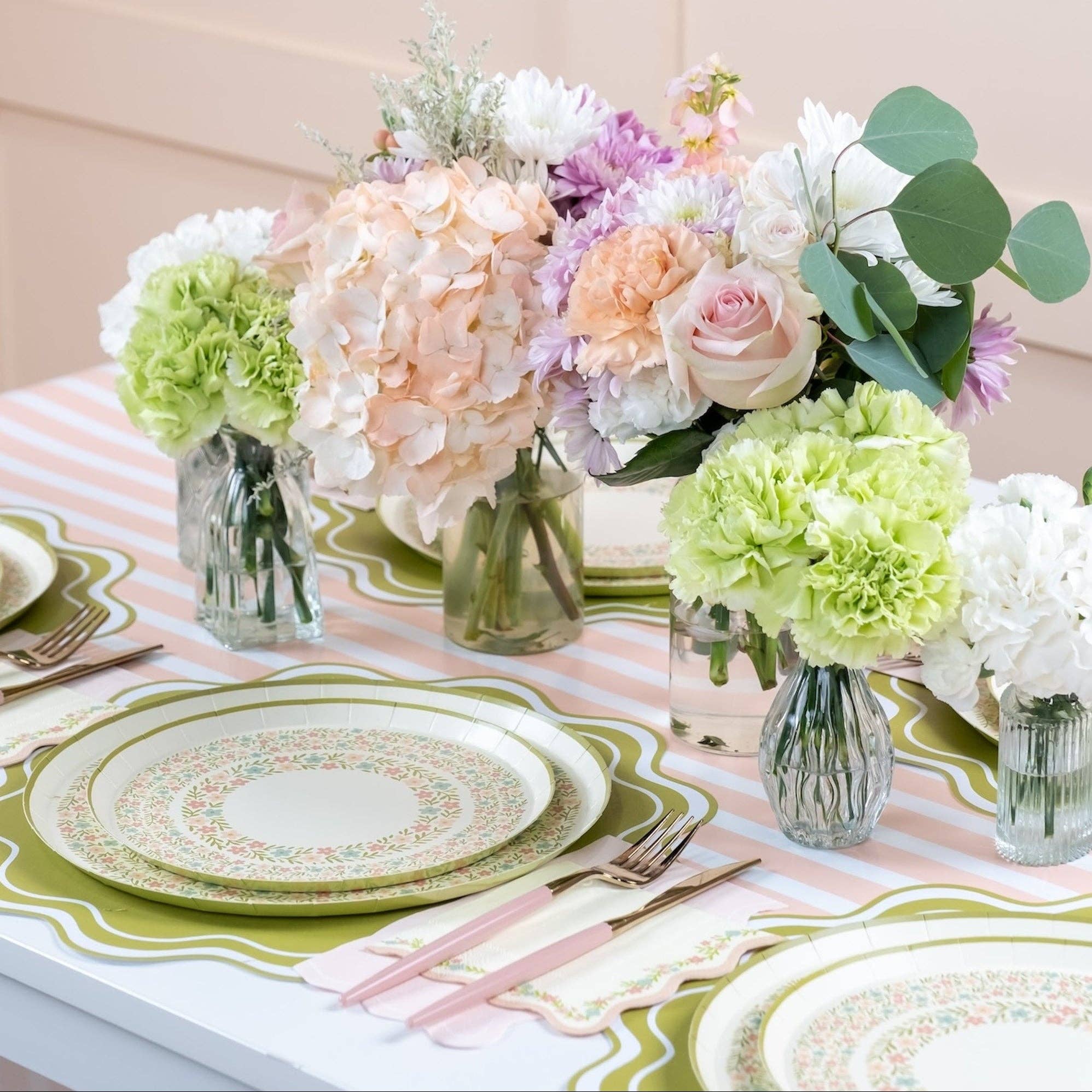 Pink striped table runner styled with pastel tableware and flowers