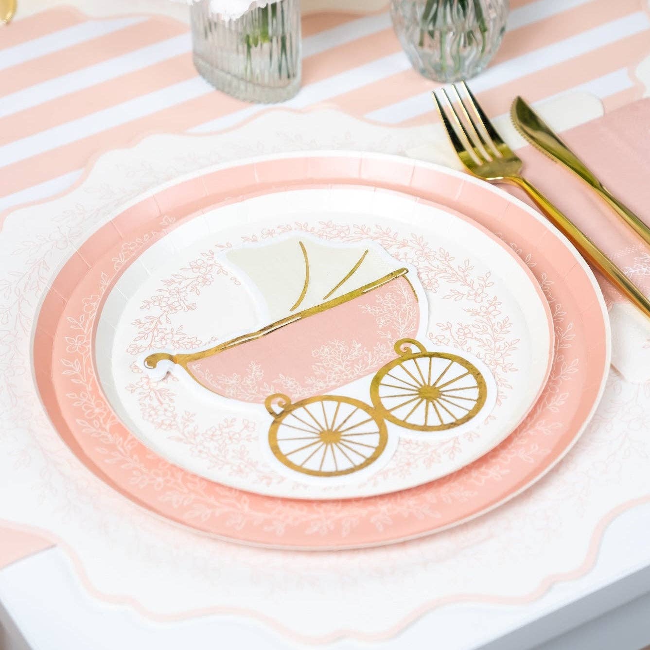 Close up of pink striped table runner with carriage plate and gold utensils