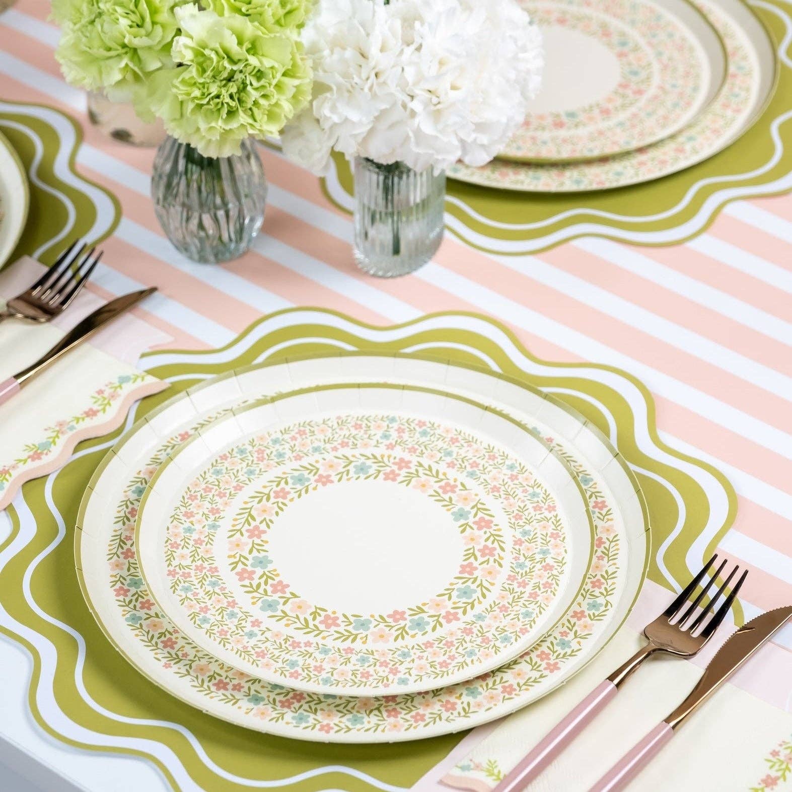 Pink striped table runner with green placemats and floral plate setting