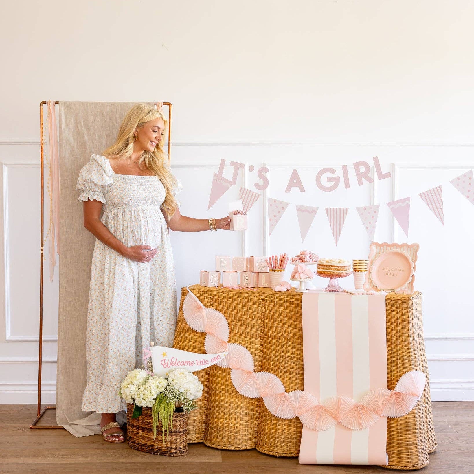 Pink tissue bunting banner hanging across girl baby shower setup
