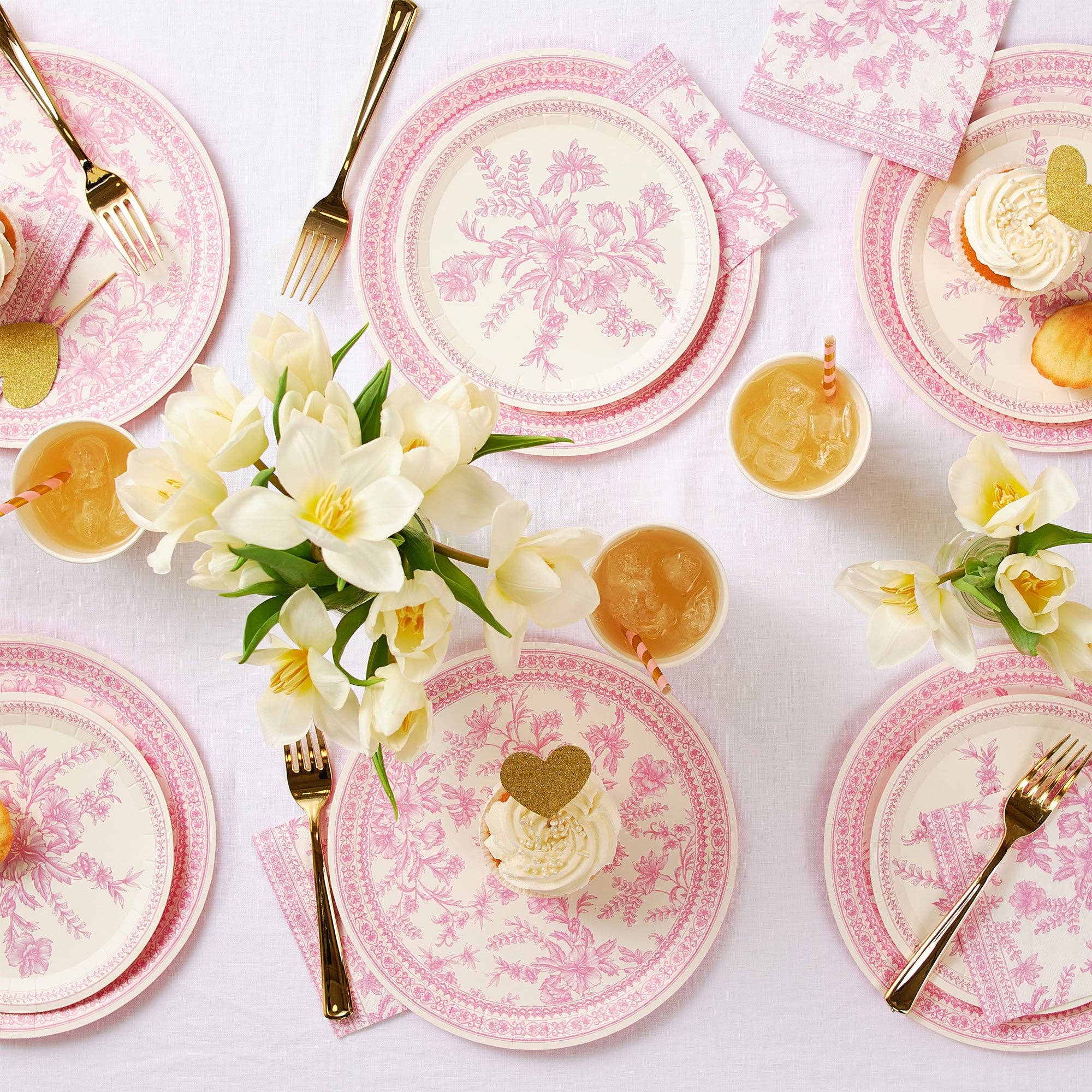 Overhead view of pink toile party table with floral arrangements.
