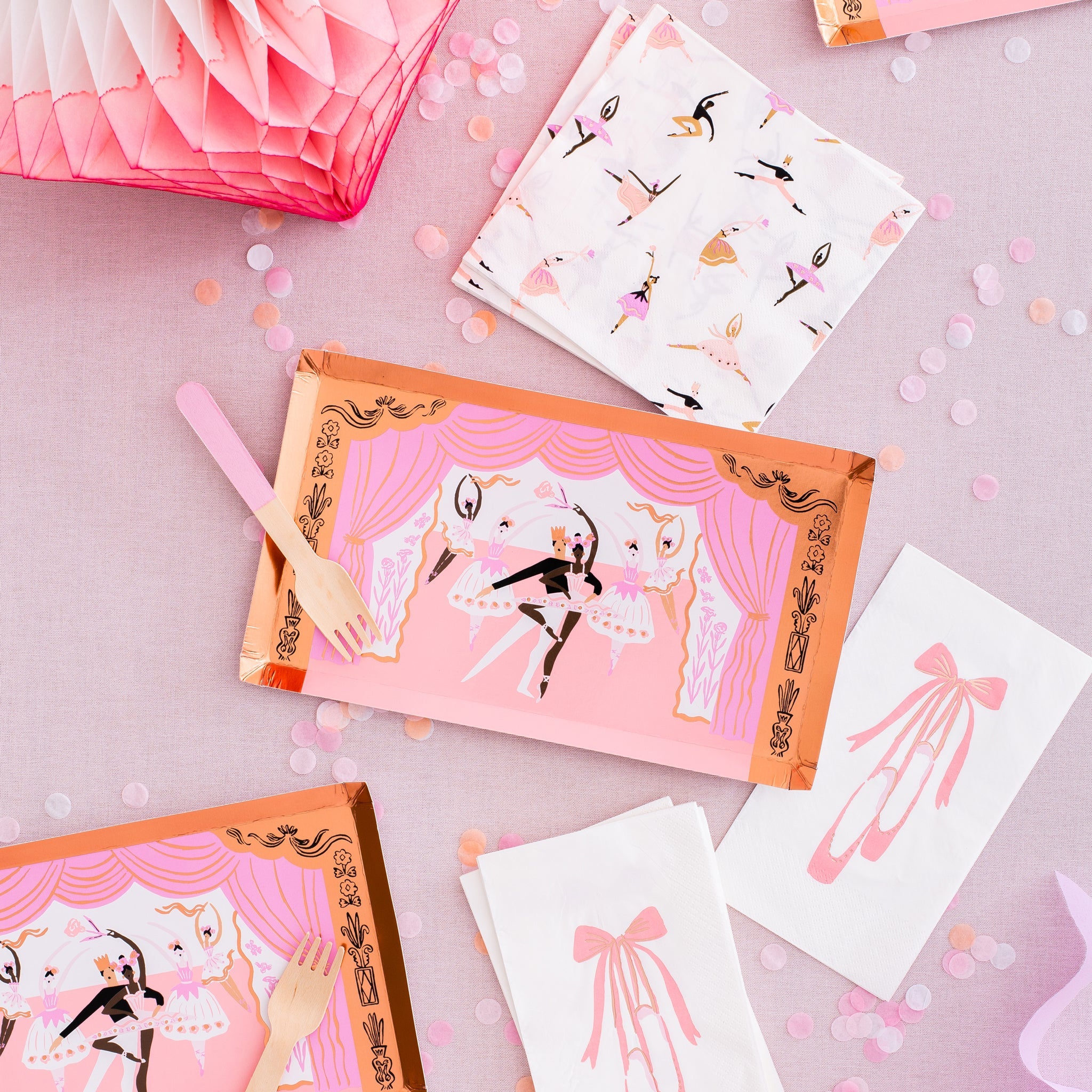 Flat lay of Pirouette party supplies including ballet dancer plates, tutu guest napkins, and pink-tipped wooden forks.