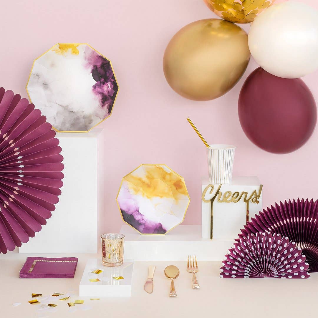 Sophisticated plum and gold party table featuring dark purple paper fans, watercolor plates, and a cheers cake topper.