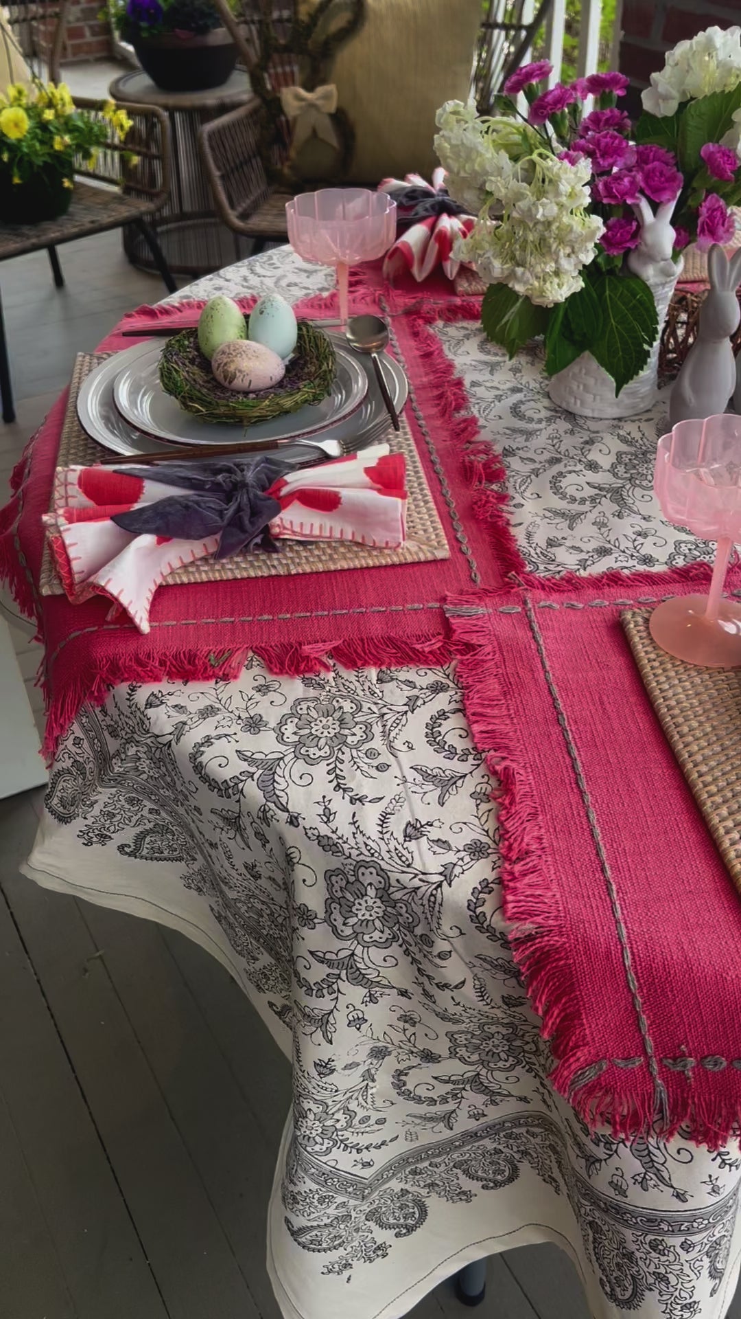 A dark gray and white floral designed tablecloth set with an Easter tablescape