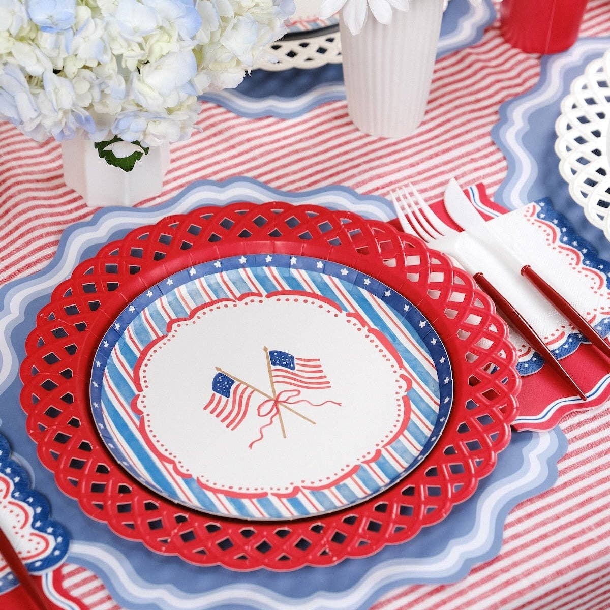 red textured paper plate layered with patriotic table setting and patterned plates.