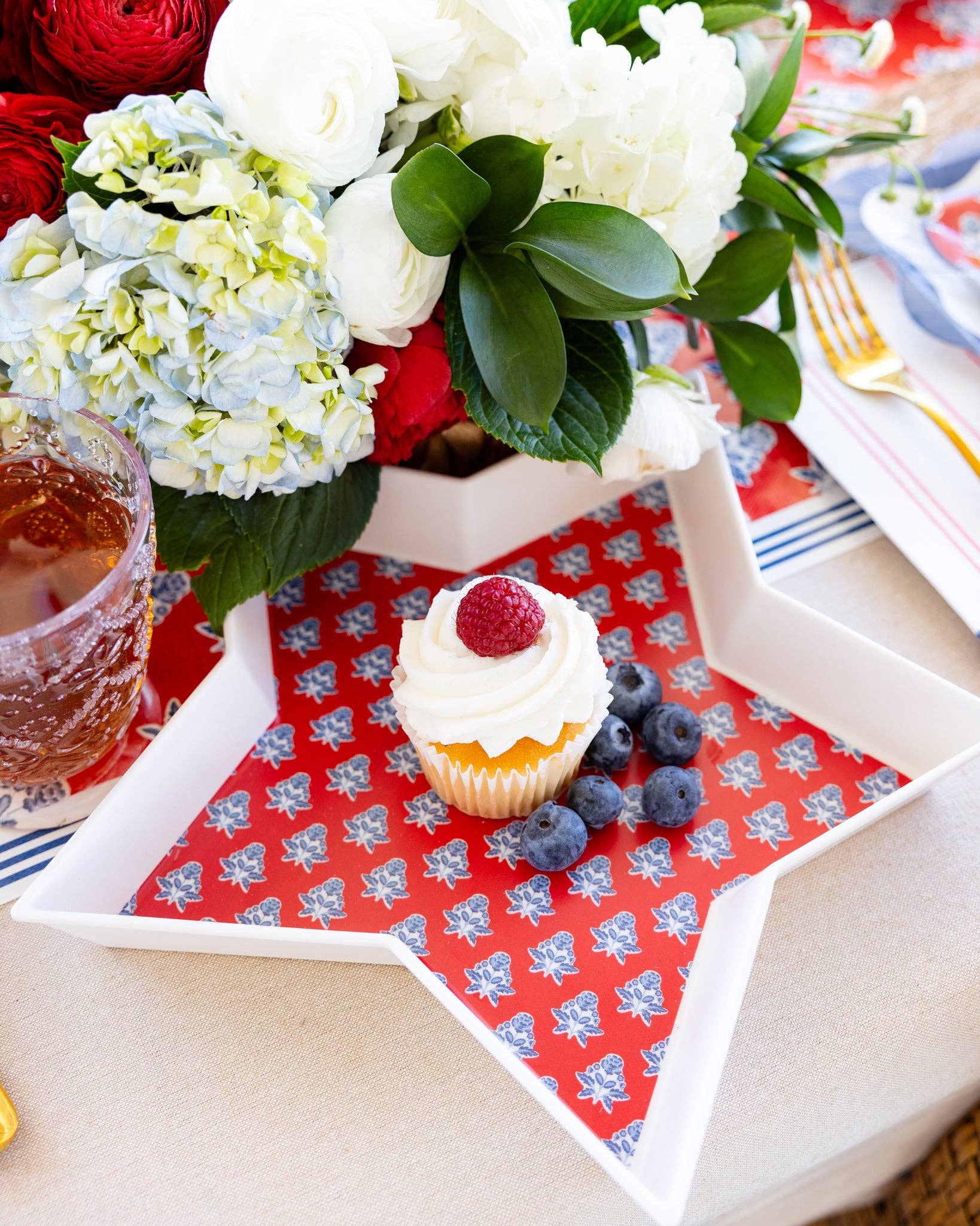 Close-up of red block print floral star bamboo tray holding a cupcake and blueberries on Americana tablescape