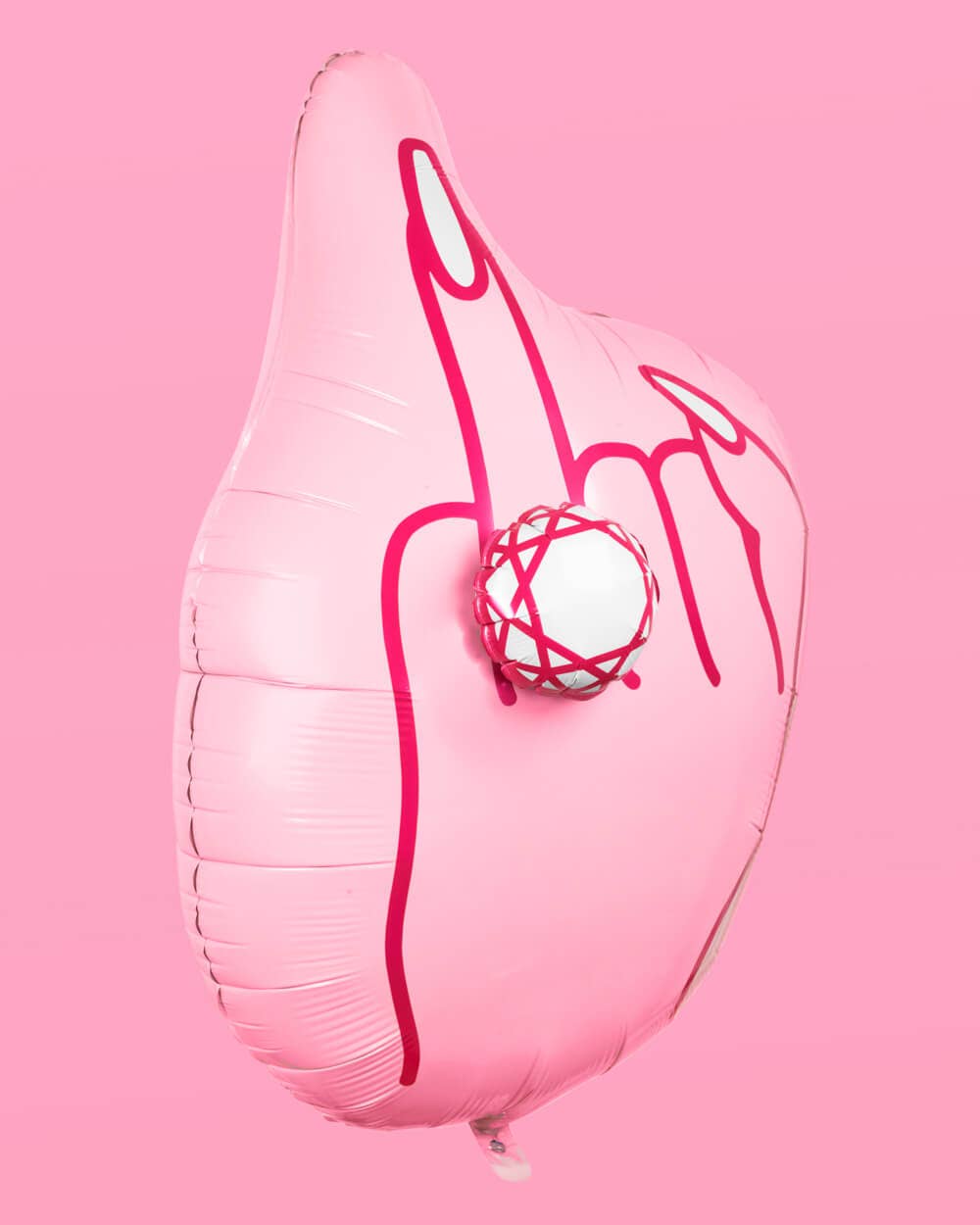 Full view of inflated pink ring finger diamond balloon floating on pink background showing hand with raised ring finger and 3D diamond