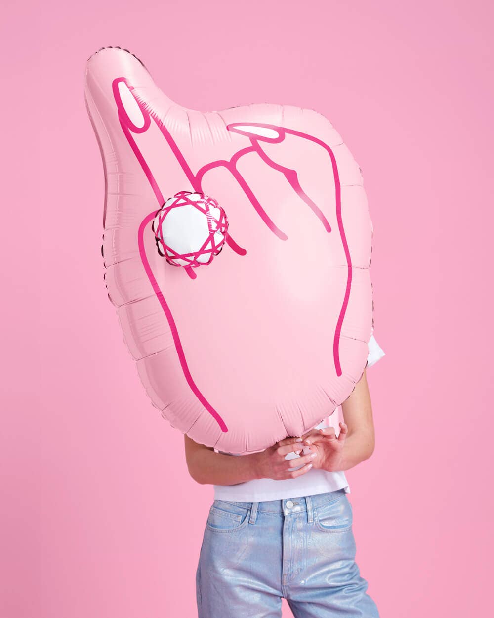 Woman holding inflated 40 inch pink ring finger diamond balloon showing hand shape with 3D diamond ring on pink background