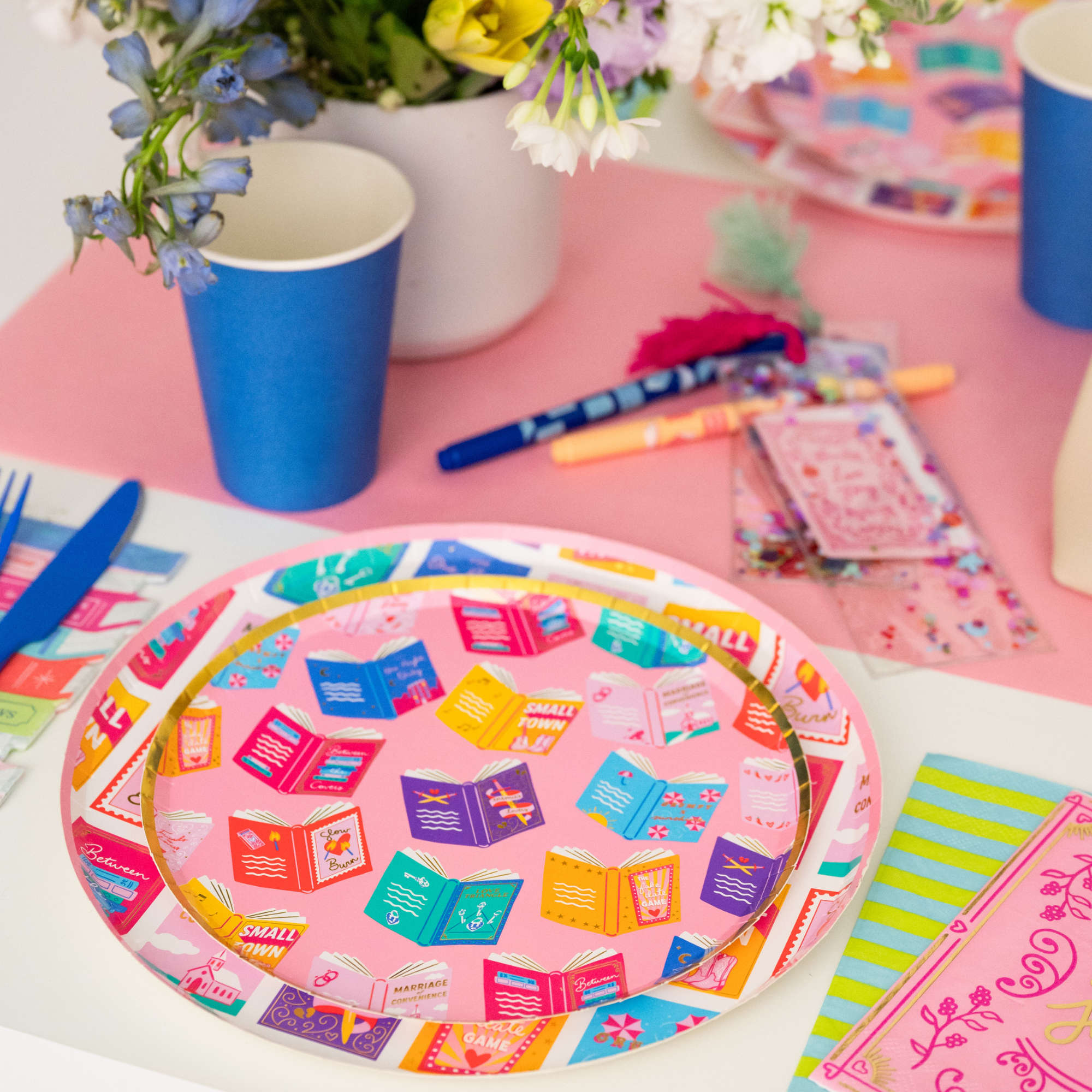 Stack of romcom plates on a colorful book club party table setup