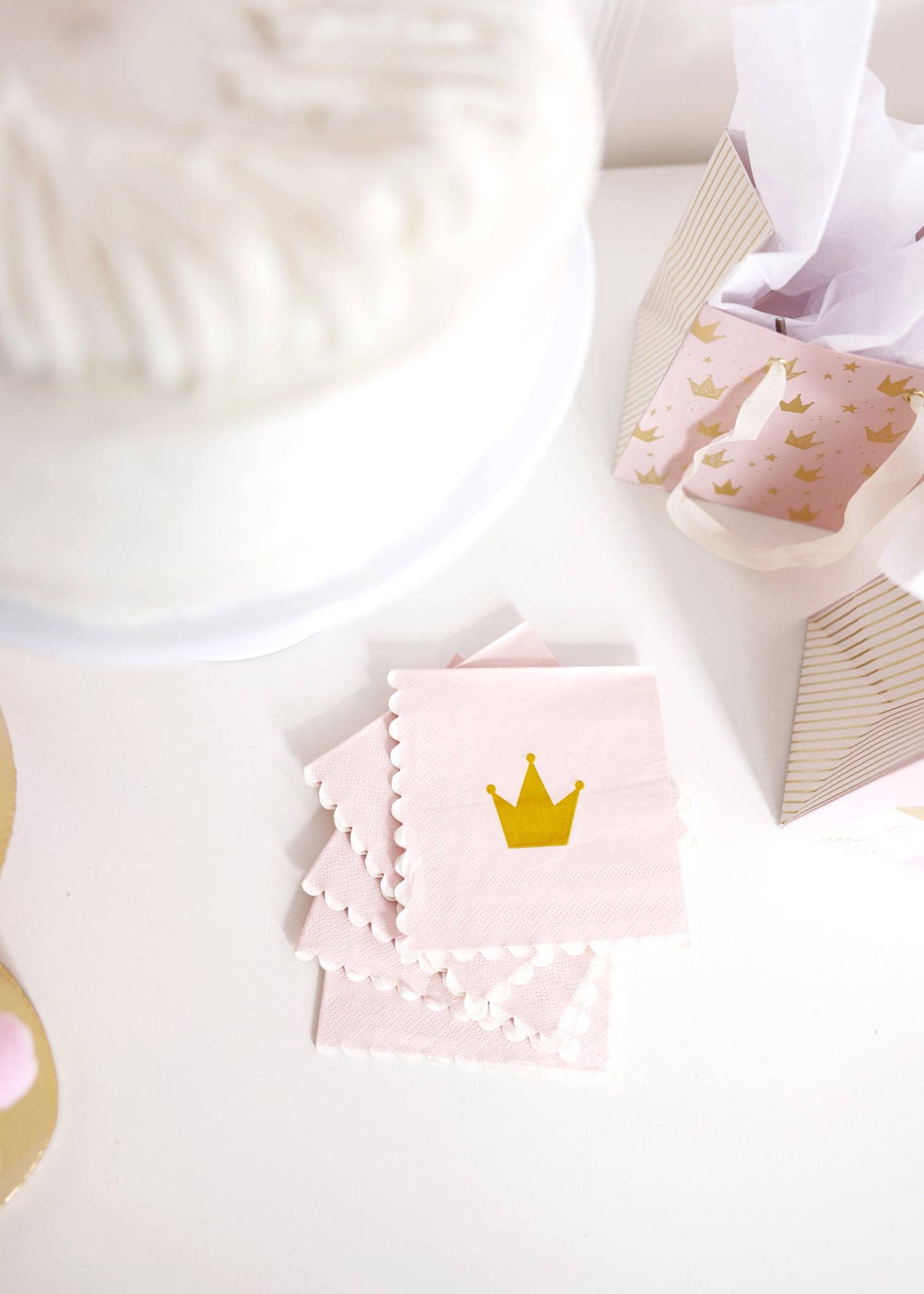 Princess Cake Napkins styled on a white table next to a cake and crown-themed gift bags.