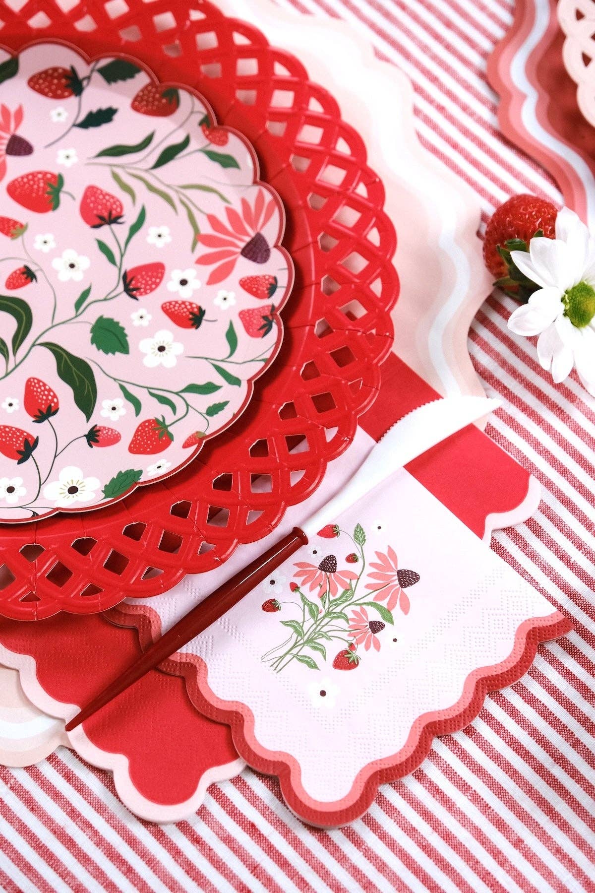 Close-up of a Strawberry Cocktail Napkin showing the red scalloped border next to a matching plate.