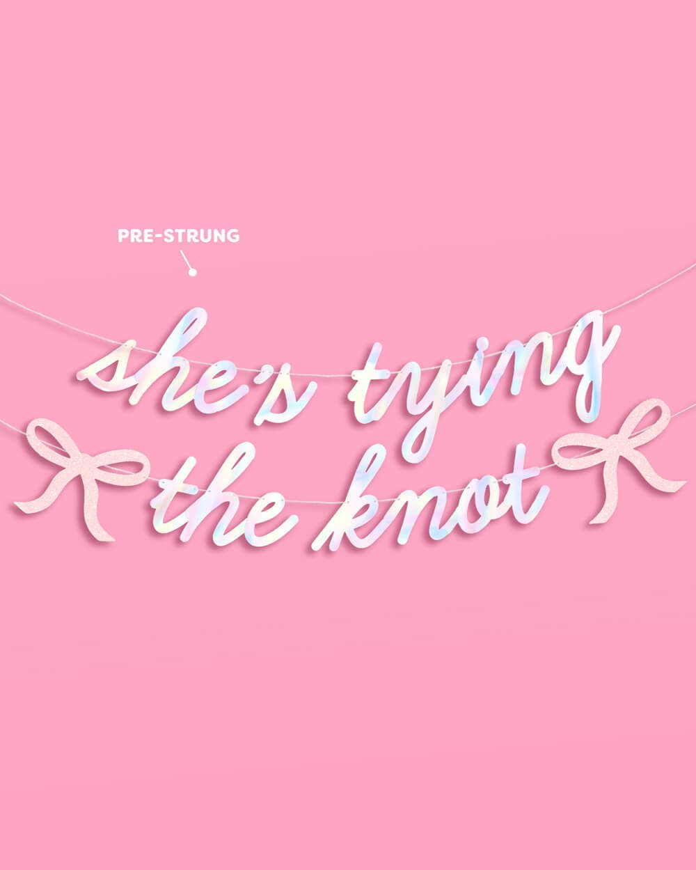 Full She's Tying the Knot iridescent foil banner with pink glitter bows pre-strung on silver cords on pink background