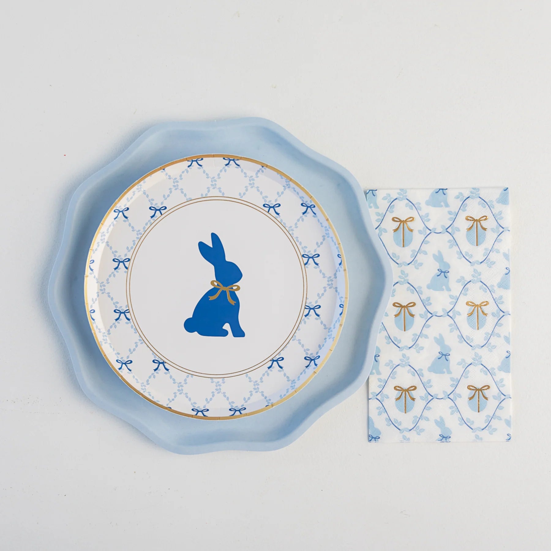 Place setting with sky blue compostable dinner plate under bunny plate and bow napkin—perfect baby shower plates.