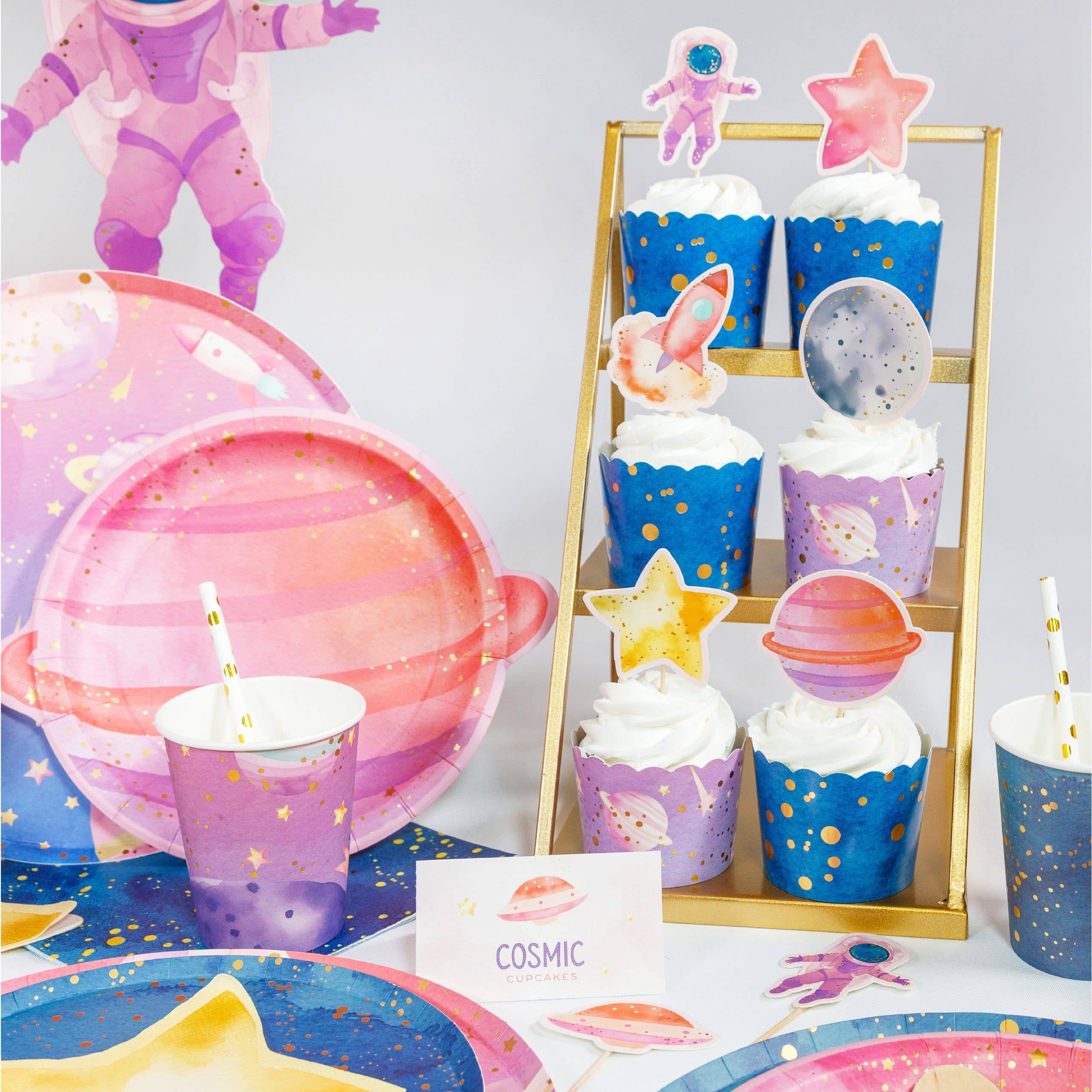 space party cupcakes displayed on stand with astronaut toppers