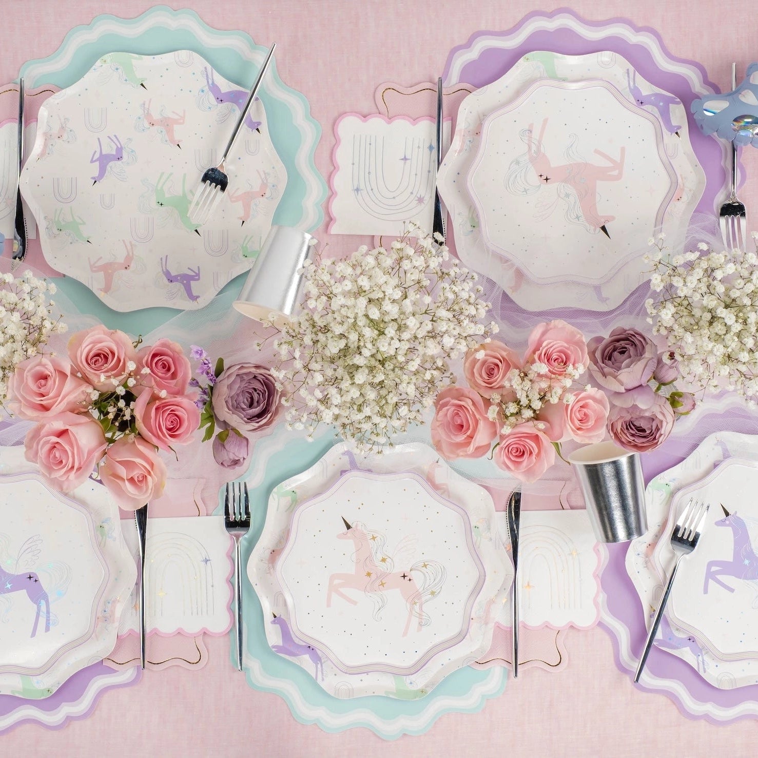 Overhead view of pastel place settings with butterflies and rainbow napkins.