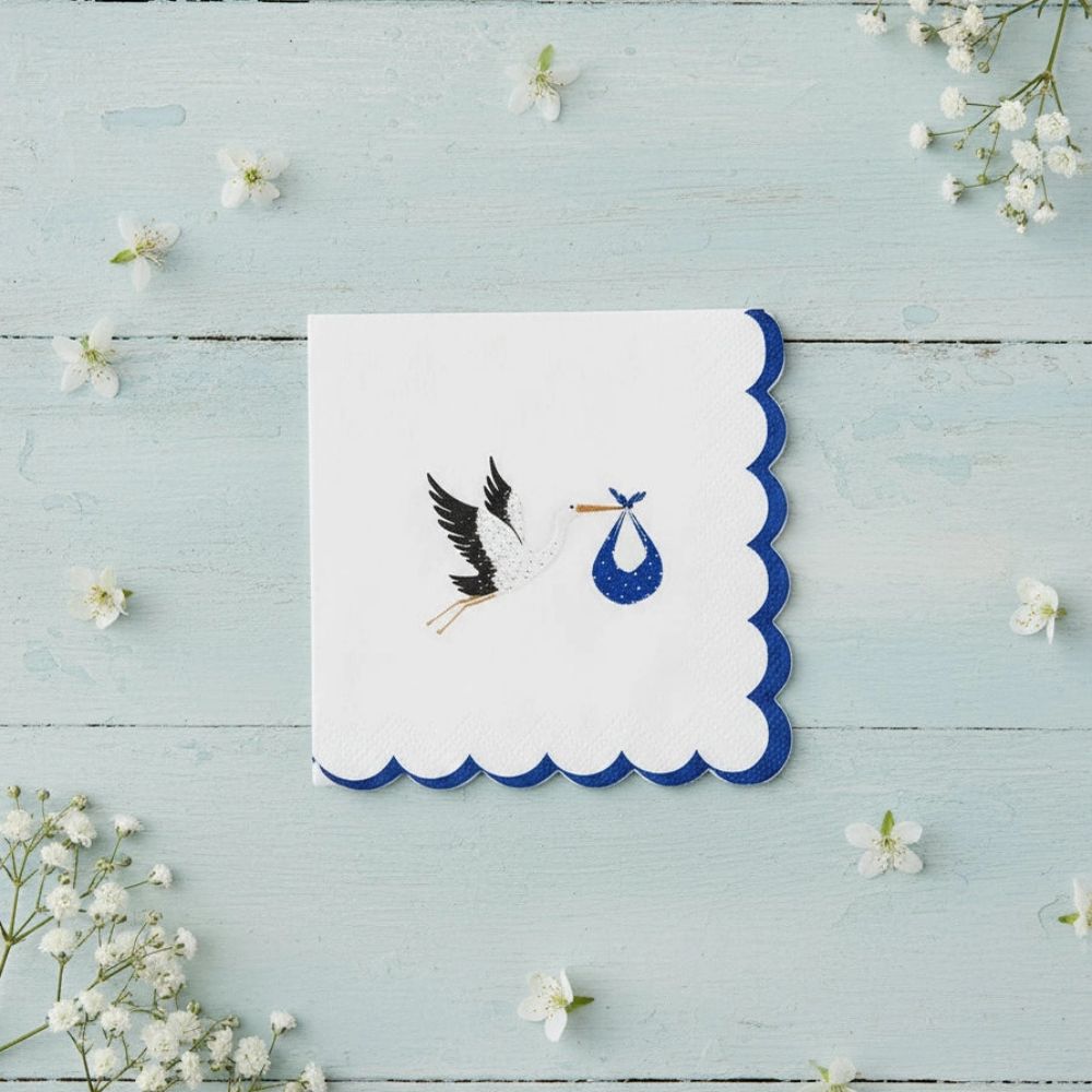Blue stork napkin centered on a light wood surface with white wildflowers