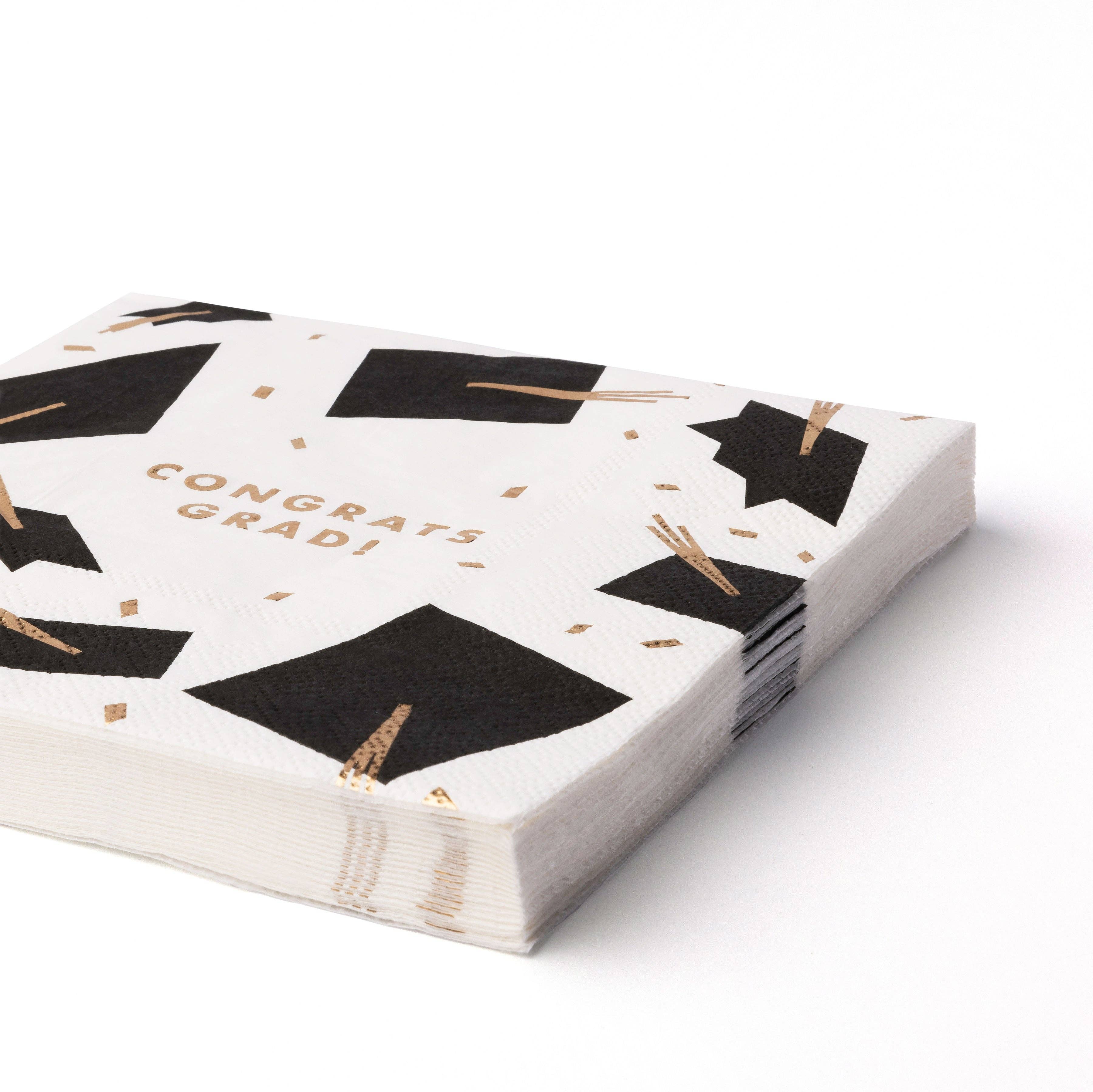 Stack of graduation lunch napkins with black caps and gold foil tassels