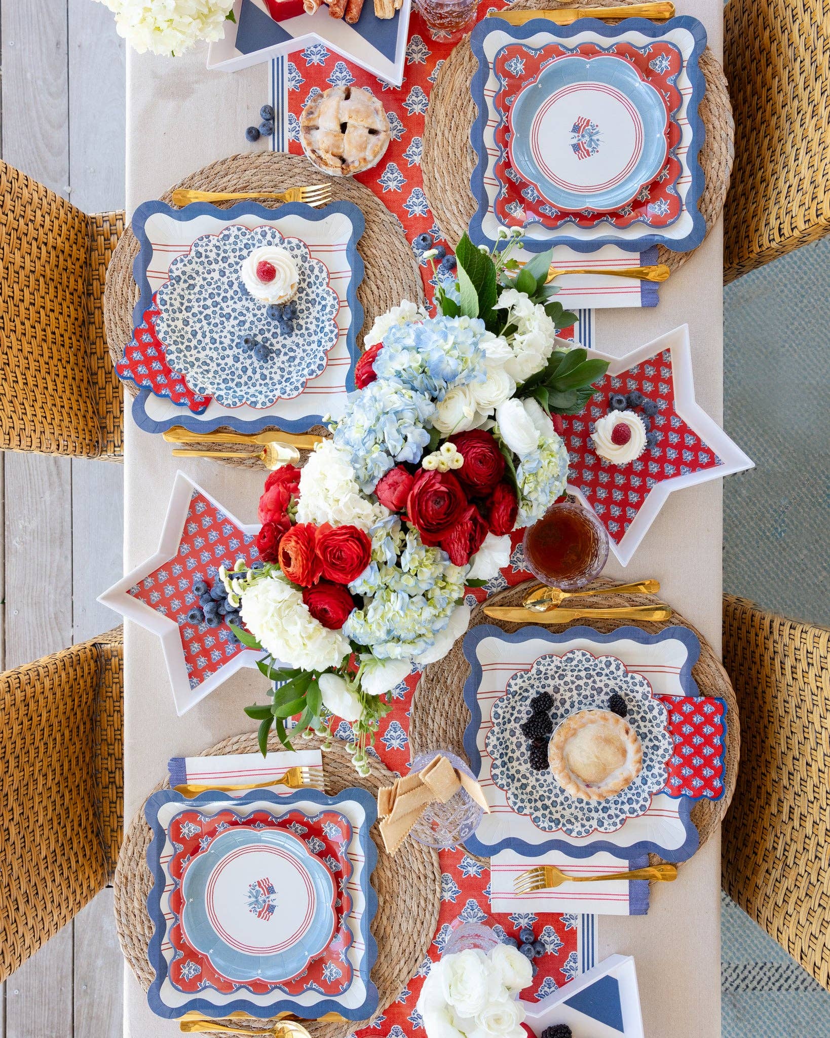 Overhead view of 4th of July tablescape with star shaped bamboo trays, scalloped paper plates, and hydrangea centerpiece