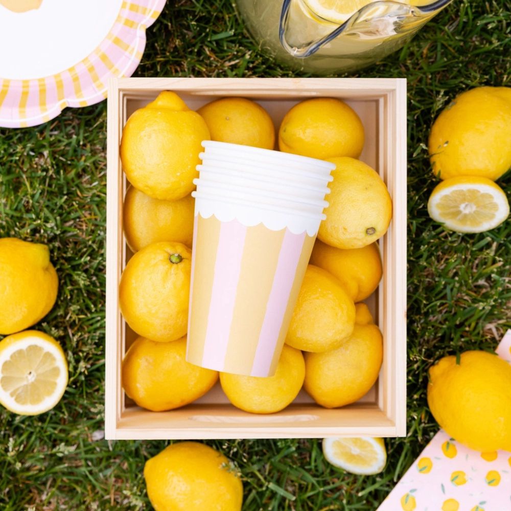 Striped party cups stacked inside wooden crate with fresh lemons