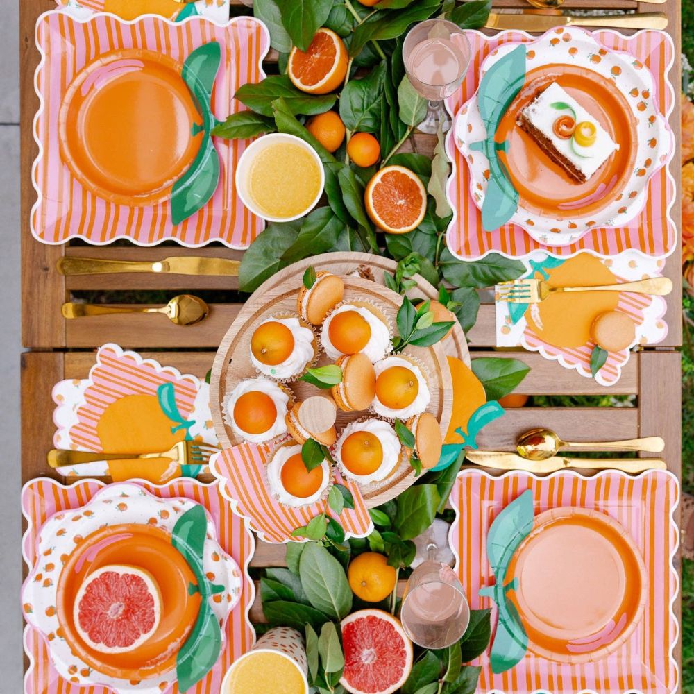 Summer citrus party table with orange and pink striped plates.
