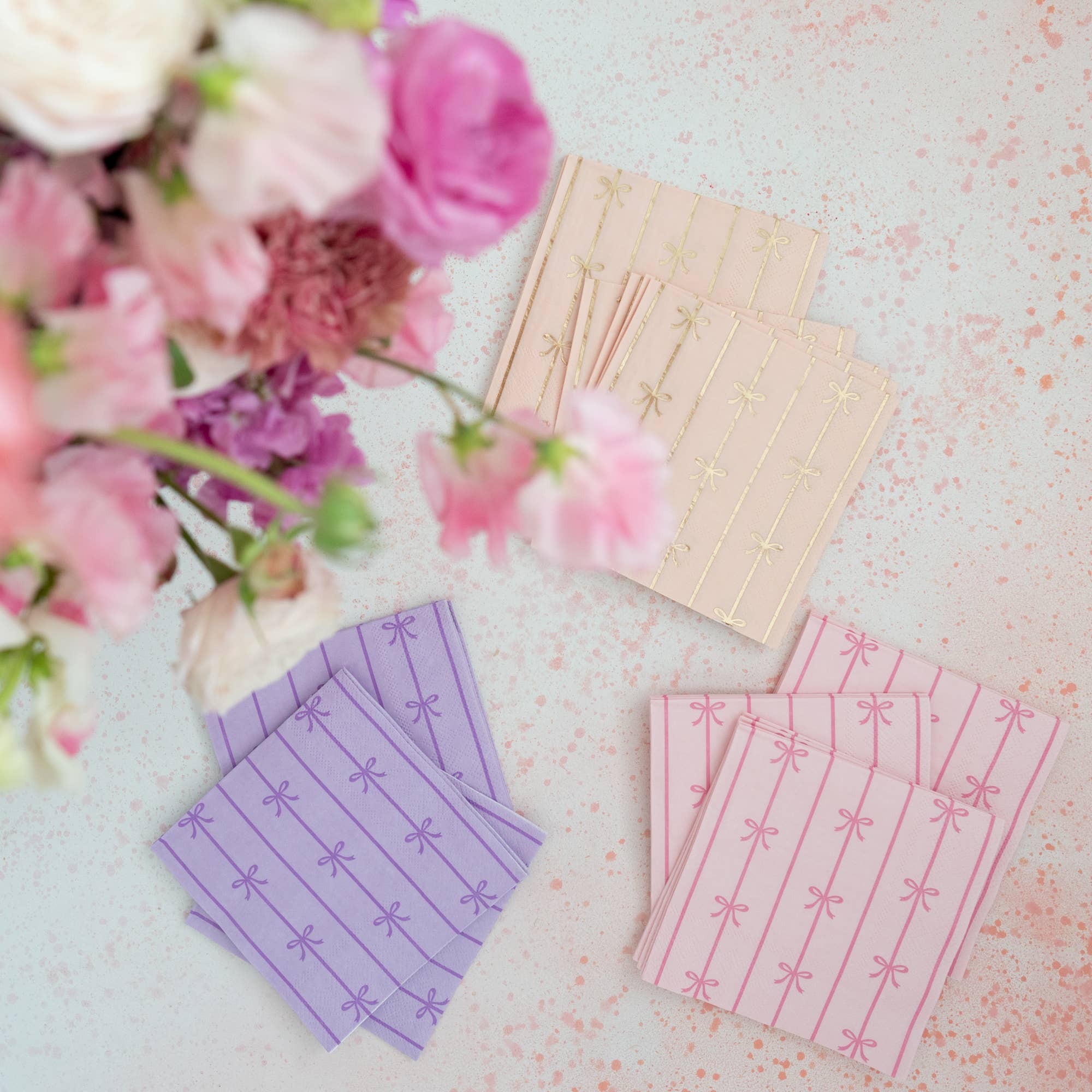 Stack of peach bow napkins styled among floral pastel party napkins