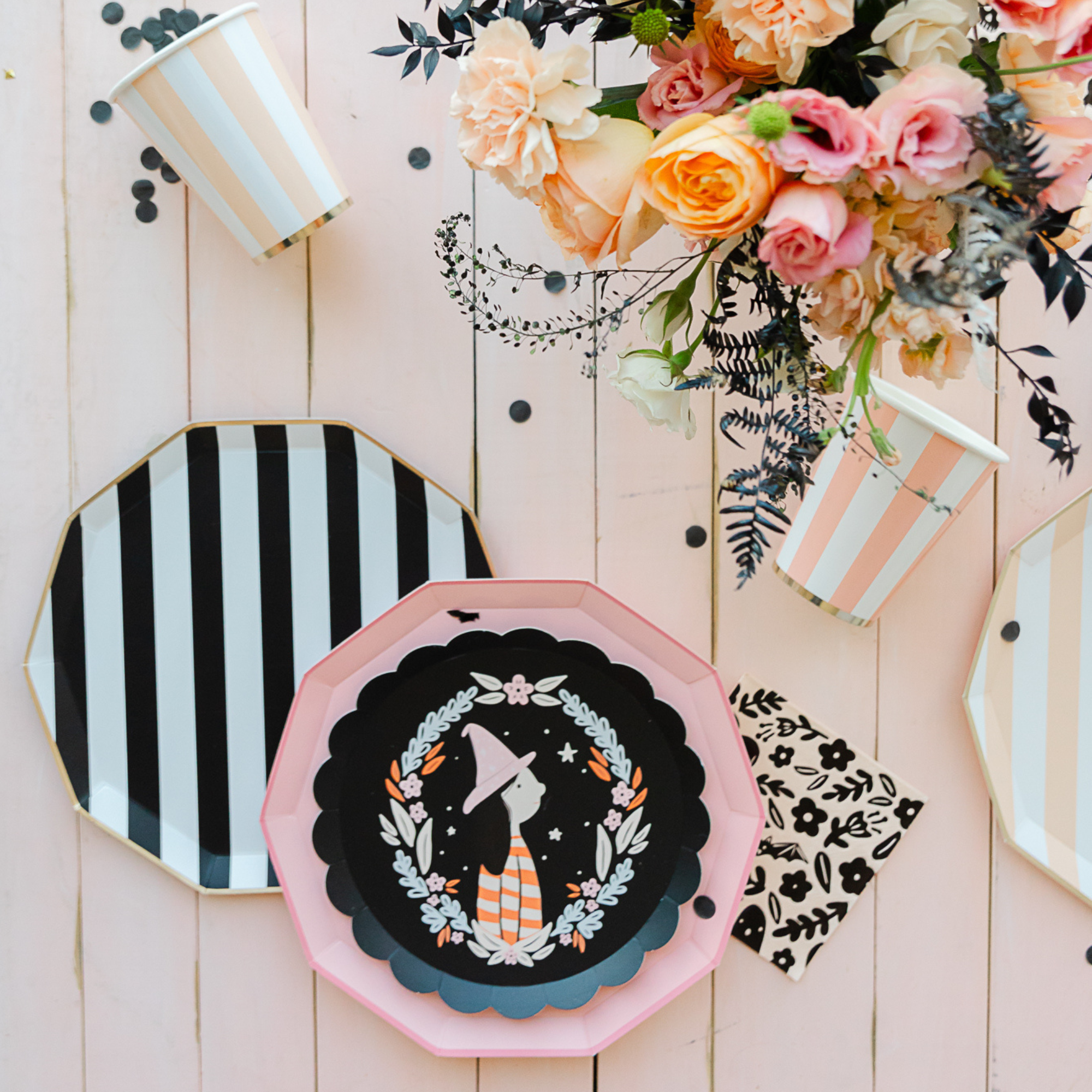 Peach cabana stripe cup on pink wood table with floral arrangement