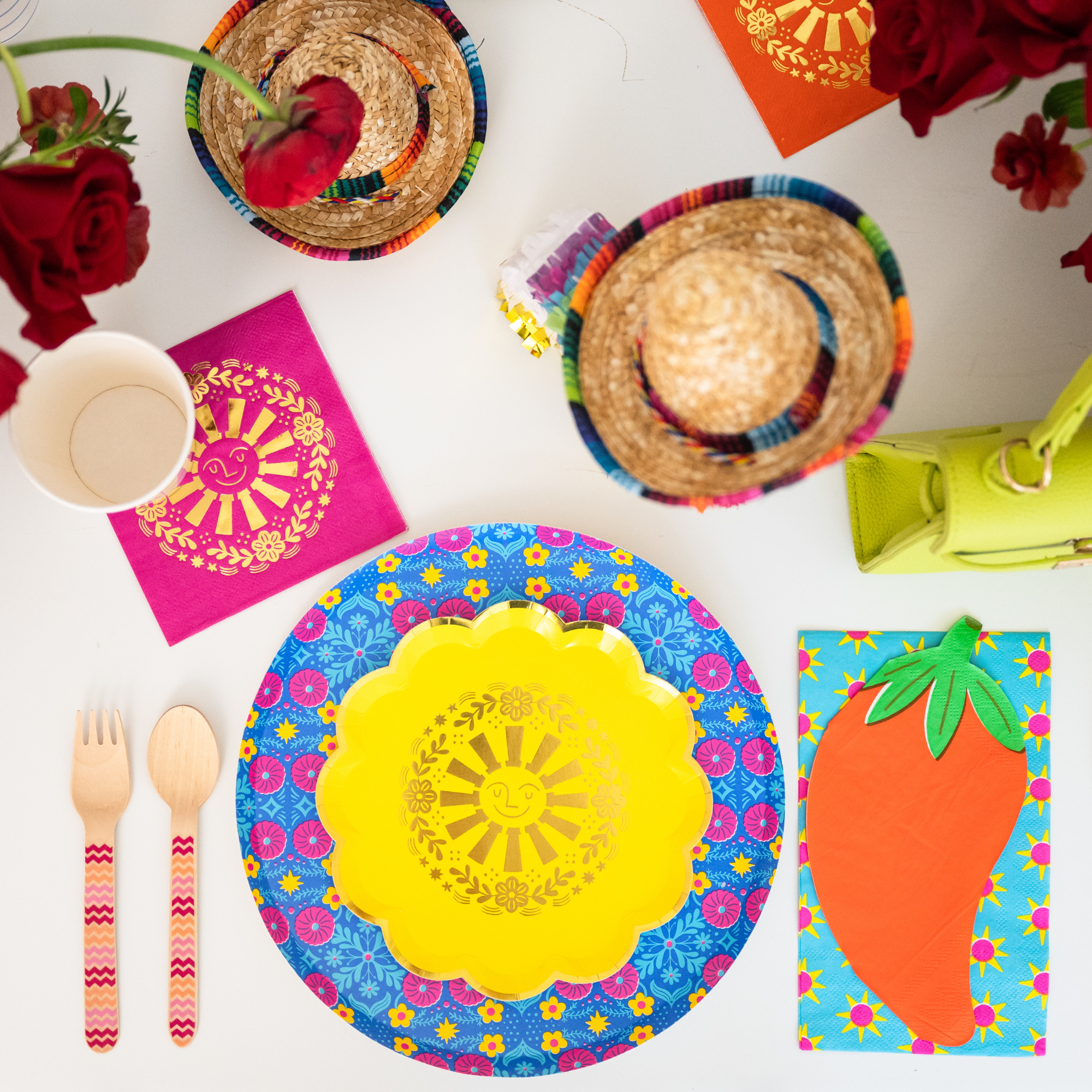 This image shows a taco-themed party table with colorful plates, sombreros, flowers, and fiesta decorations.
